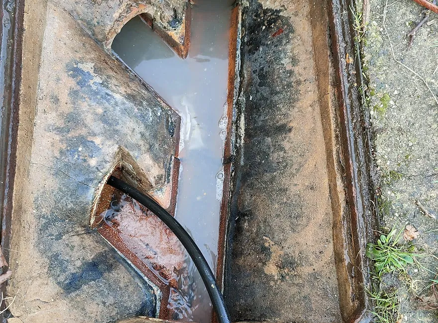 an old rusty drain with a hose in it